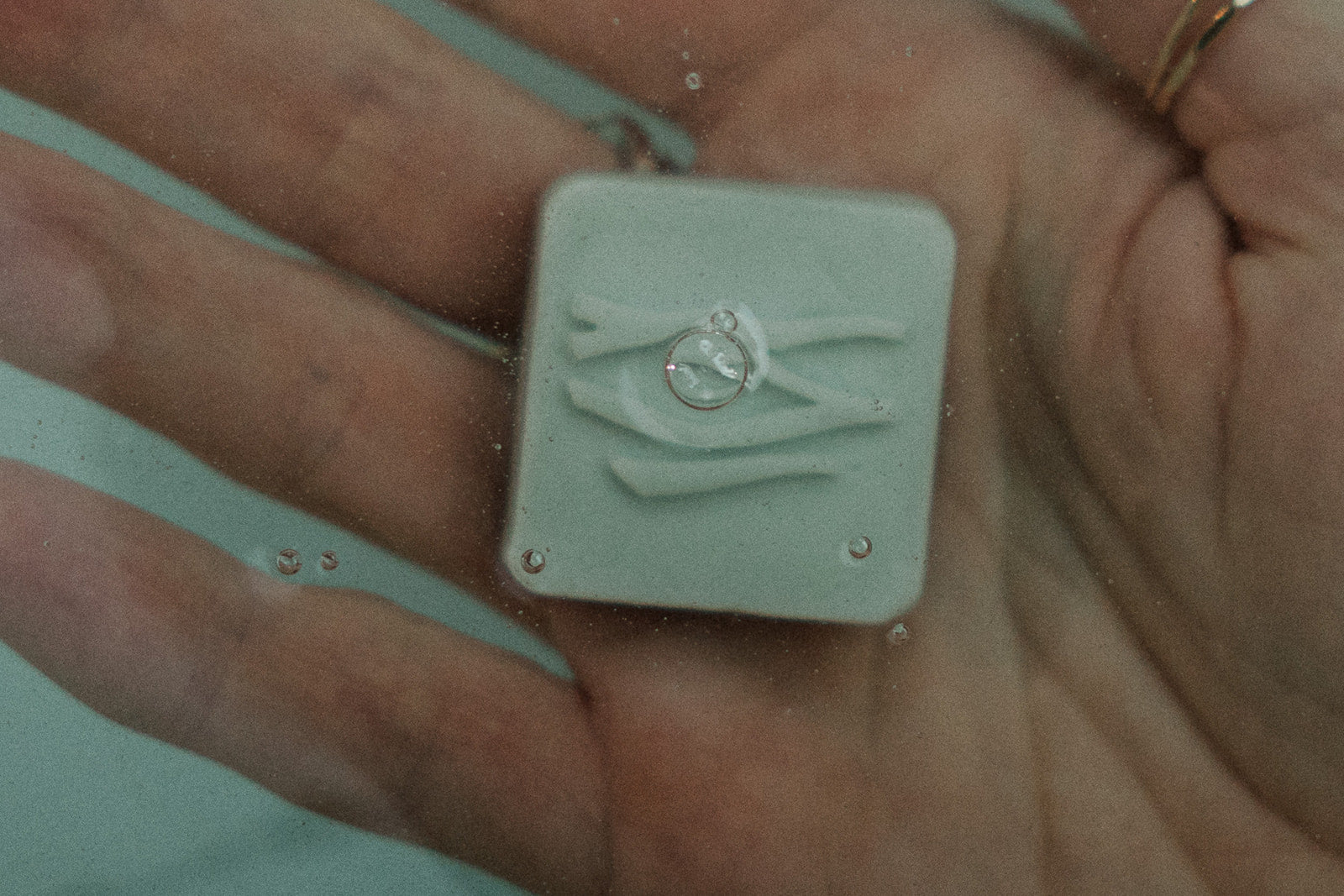 A cleaning bar being held under water on a hand.